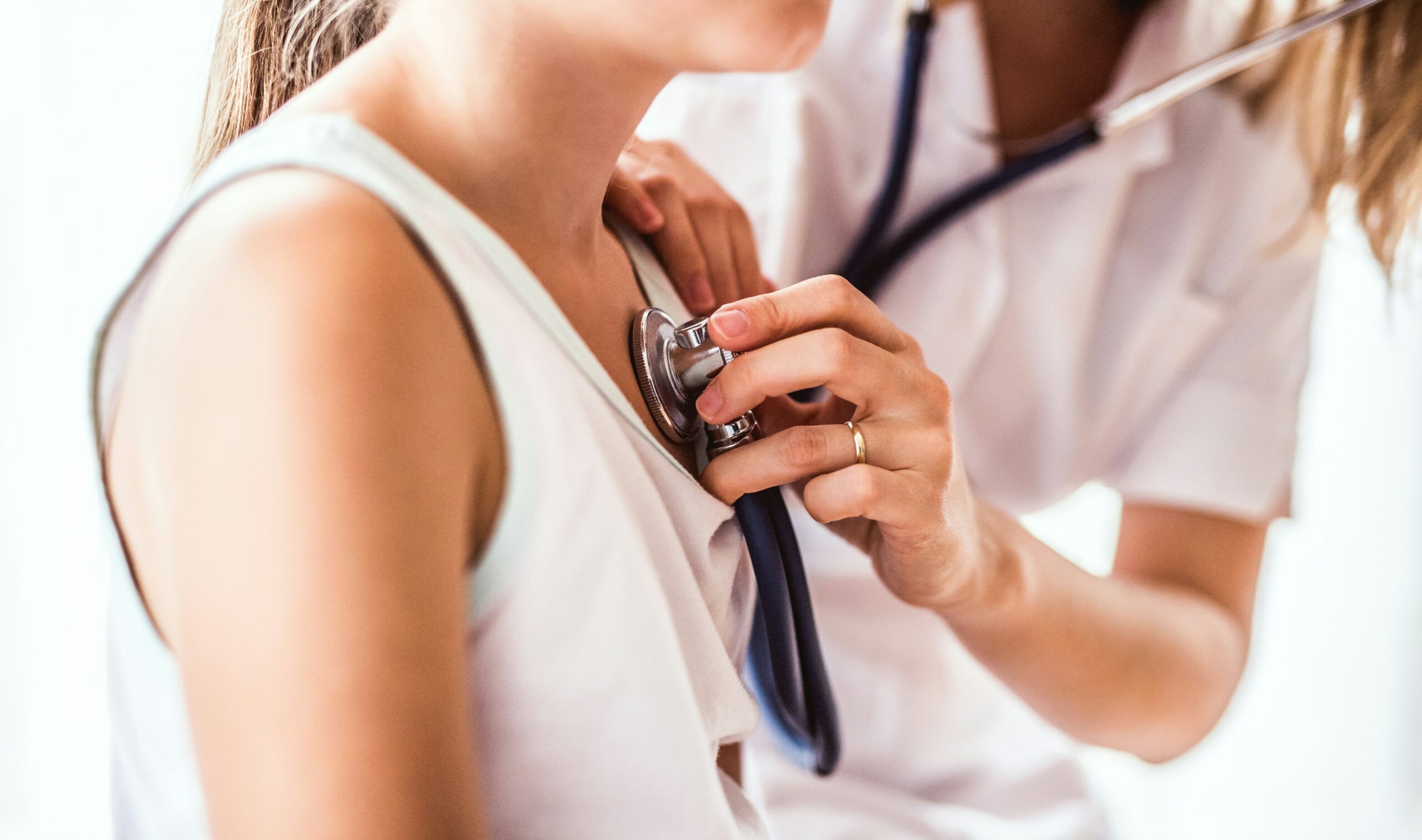 Consultation médicale avec auscultation cardiaque au stéthoscope – dépistage des anomalies du rythme chez une patiente jeune